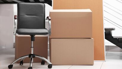 A black leather office chair next to a stack of moving boxing in a corporate office.