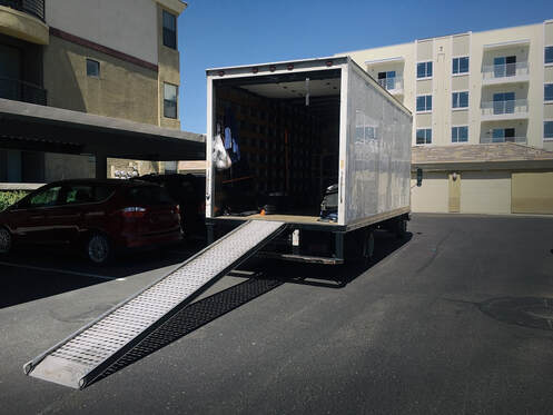 A large moving truck with moving supplies and an extended ramp ready for loading.